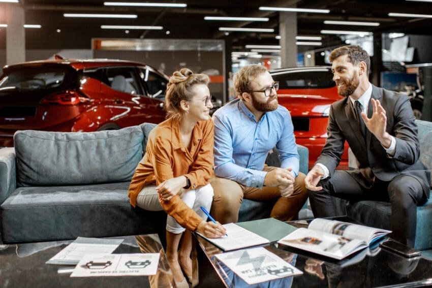 Young,Couple,With,Sales,Manager,On,The,Comfortable,Couch,At