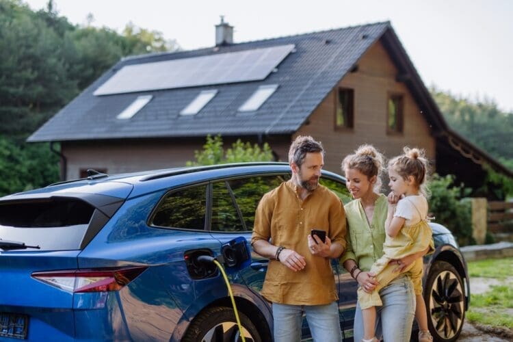 family with electric car charging from solar panels on house