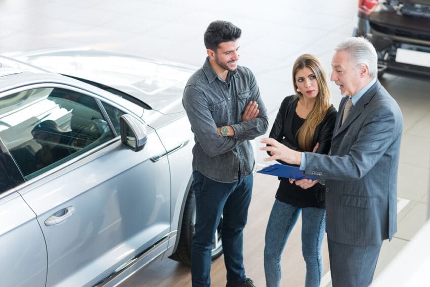 Happy,Young,Family,Talking,To,The,Salesman,And,Choosing,Their